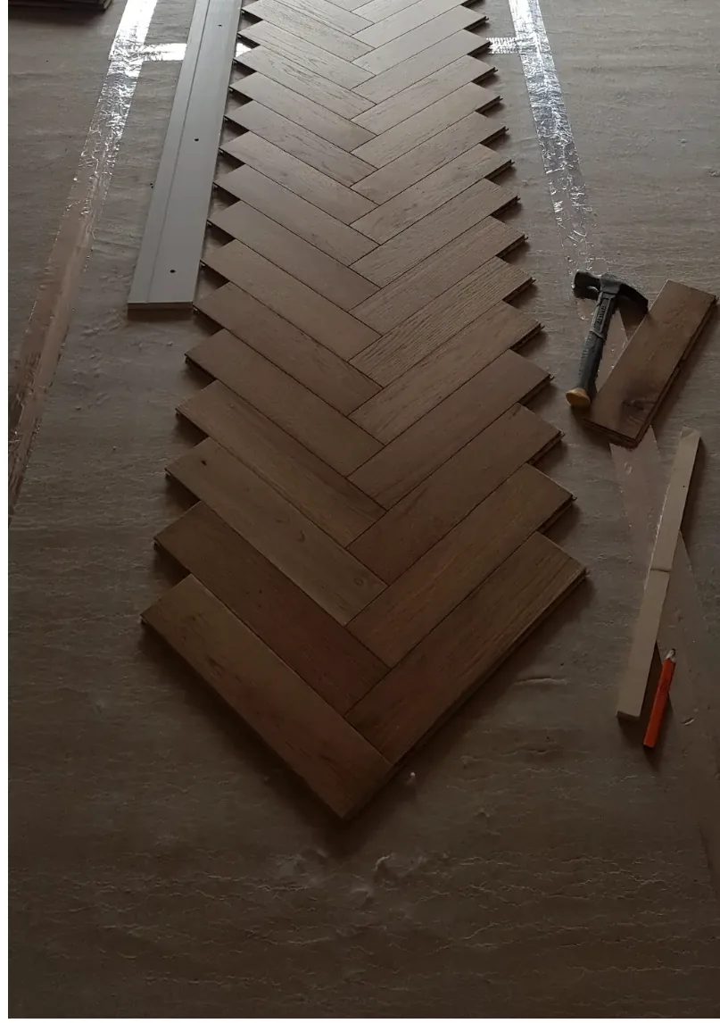 Herringbone parquet flooring being set out and laid block by block over underlay
