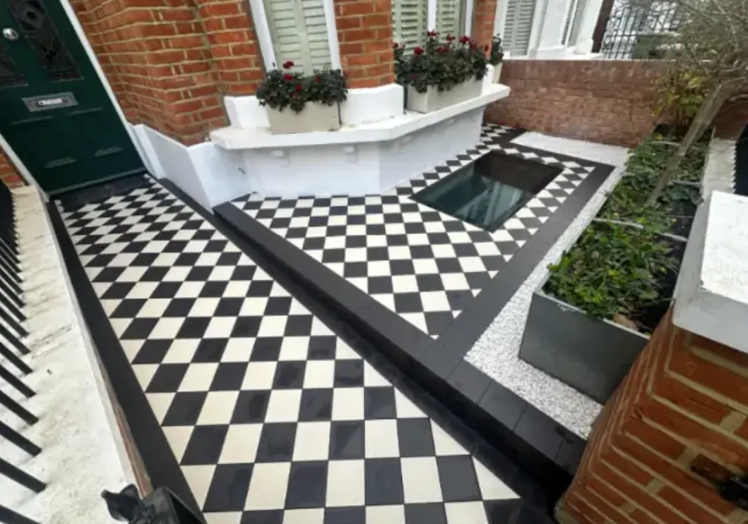 Victorian style black and white geometric mosaic tiled front path and step to a green front door